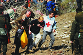 Foto: Ein Rotkreuzhelfer stützt Flüchtlinge, um durch die Grenzzone zu kommen - vorbei an bewaffneten Männern.